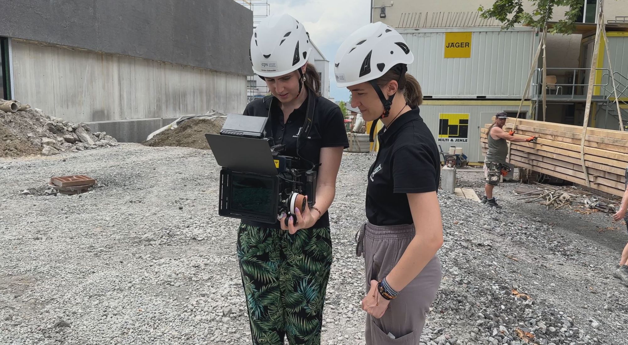 zwei junge frauen filmen mit einer kamera auf einer baustelle